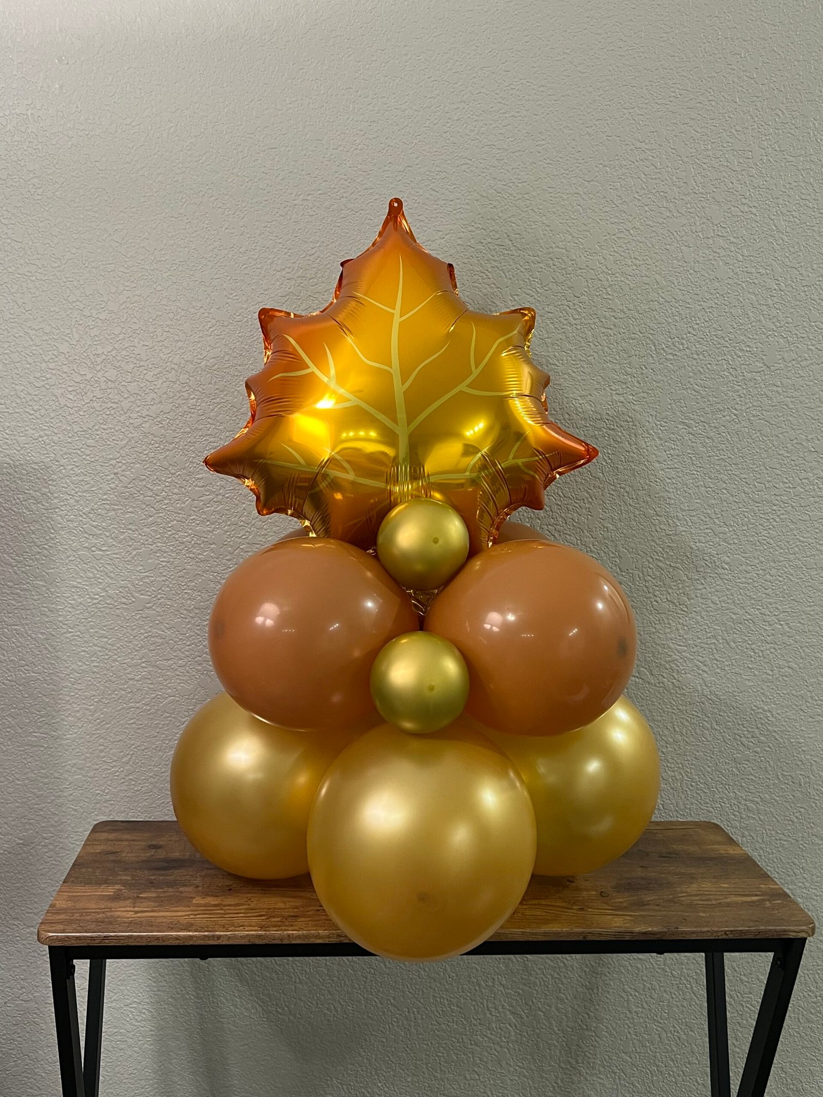 Gold maple leaf balloon with warm brown and gold balloon clusters