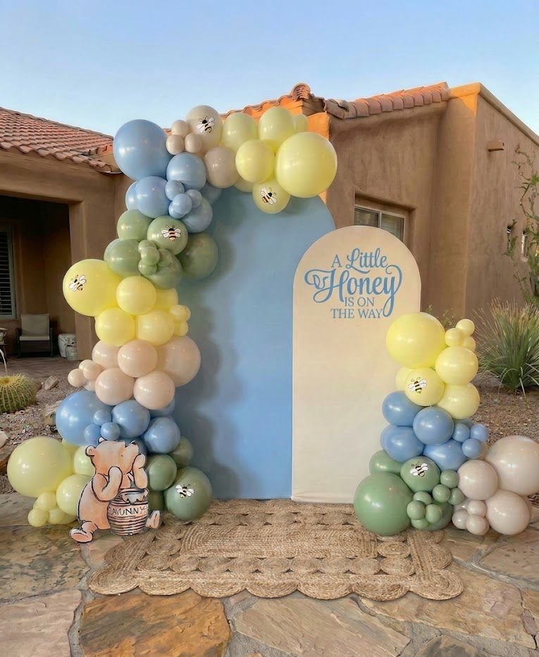 Pastel blue and yellow balloons around an outdoor birthday backdrop