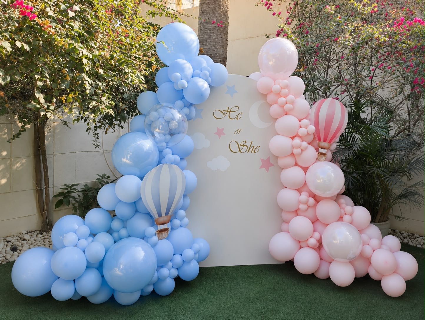 Pink and blue balloons surrounding an outdoor baby celebration backdrop