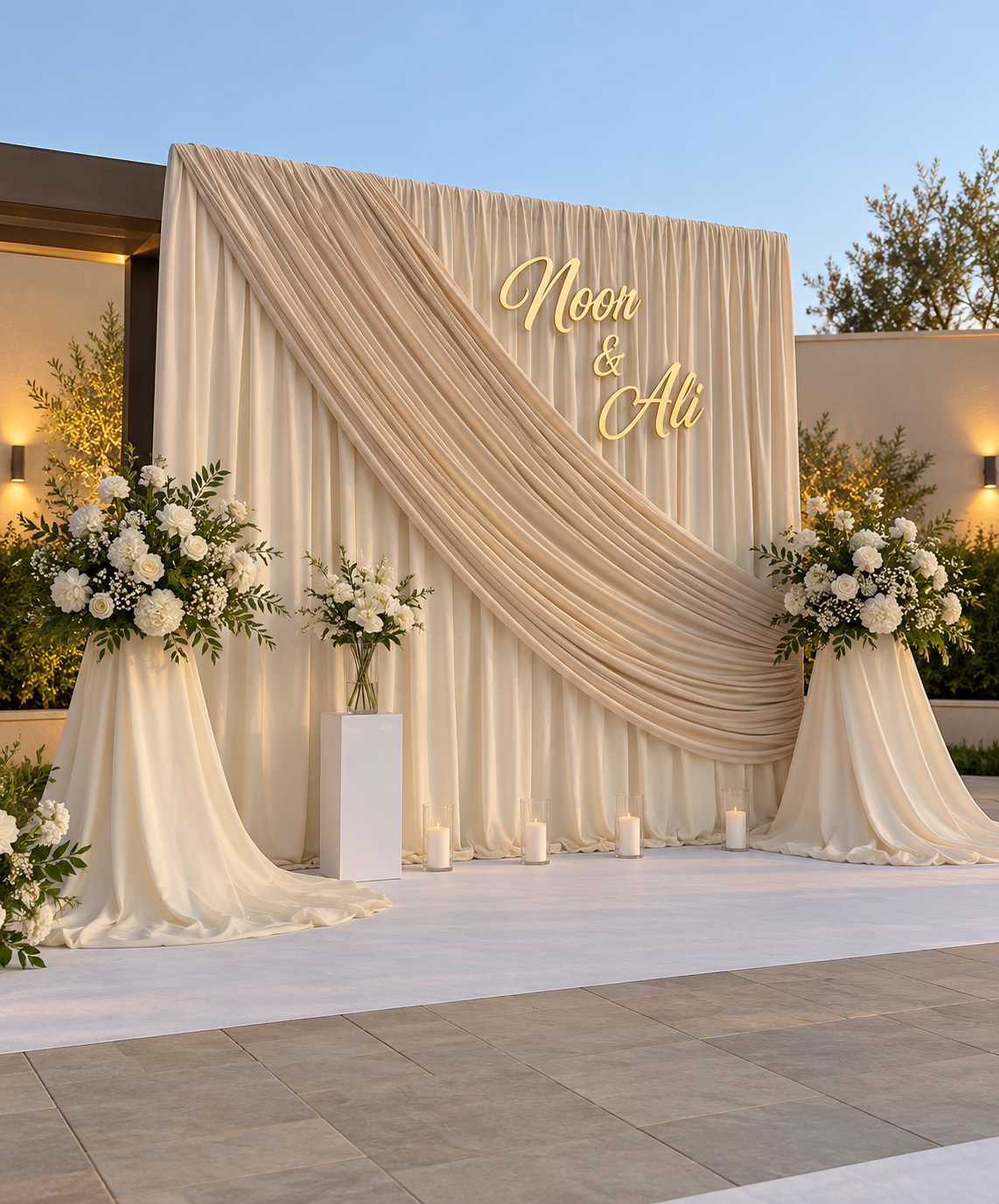 Ivory draped wedding backdrop with gold names, white flowers and candles