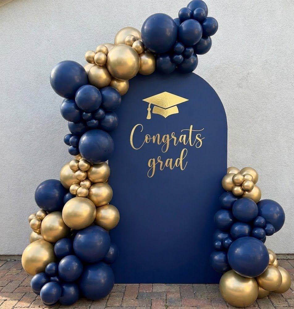 Navy blue and gold balloons around a Congrats grad arch backdrop